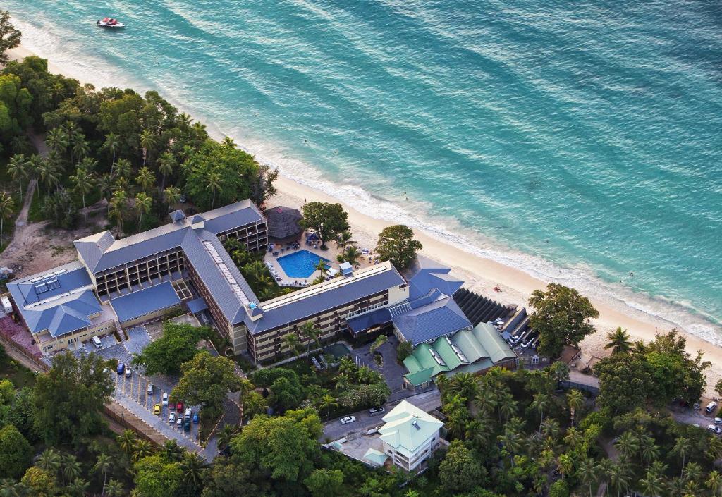 Aerial view of Coral Strand Smart Choice on Beau Vallon beach, with the hotel buildings, pool and gardens behind the sand