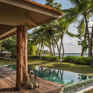Villa terrace with a private pool, lawn and palm trees facing the sea at Four Seasons Desroches Island