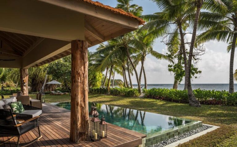 Villa terrace with a private pool, lawn and palm trees facing the sea at Four Seasons Desroches Island