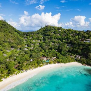 Aerial view of Four Seasons Resort Seychelles villas spread across the wooded hillside above the beach at Petite Anse, Mahé