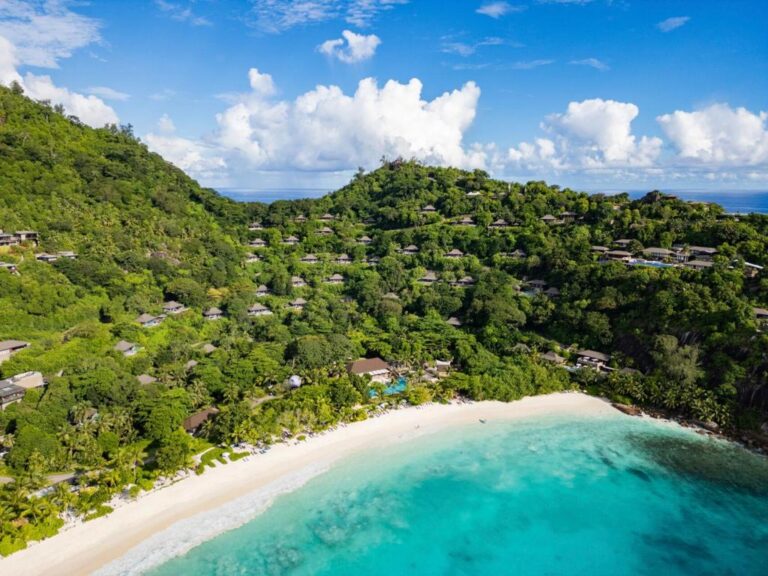 Aerial view of Four Seasons Resort Seychelles villas spread across the wooded hillside above the beach at Petite Anse, Mahé