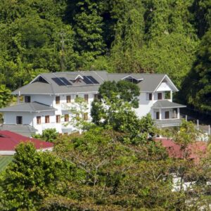 White three-storey Hilltop Boutique Hotel building set among trees on the hillside above Victoria