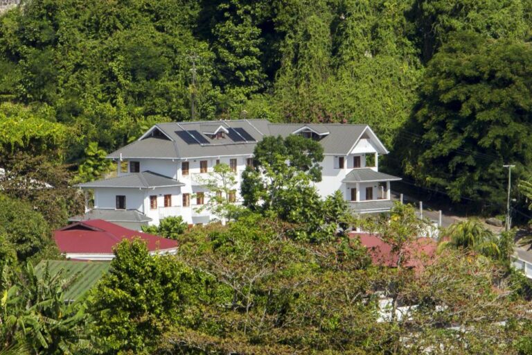 White three-storey Hilltop Boutique Hotel building set among trees on the hillside above Victoria