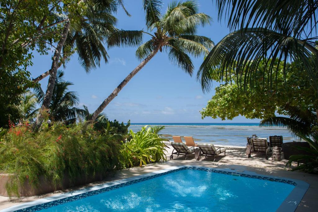 Pool and sun loungers under palm trees beside the beach at Le Repaire, Anse Réunion, La Digue