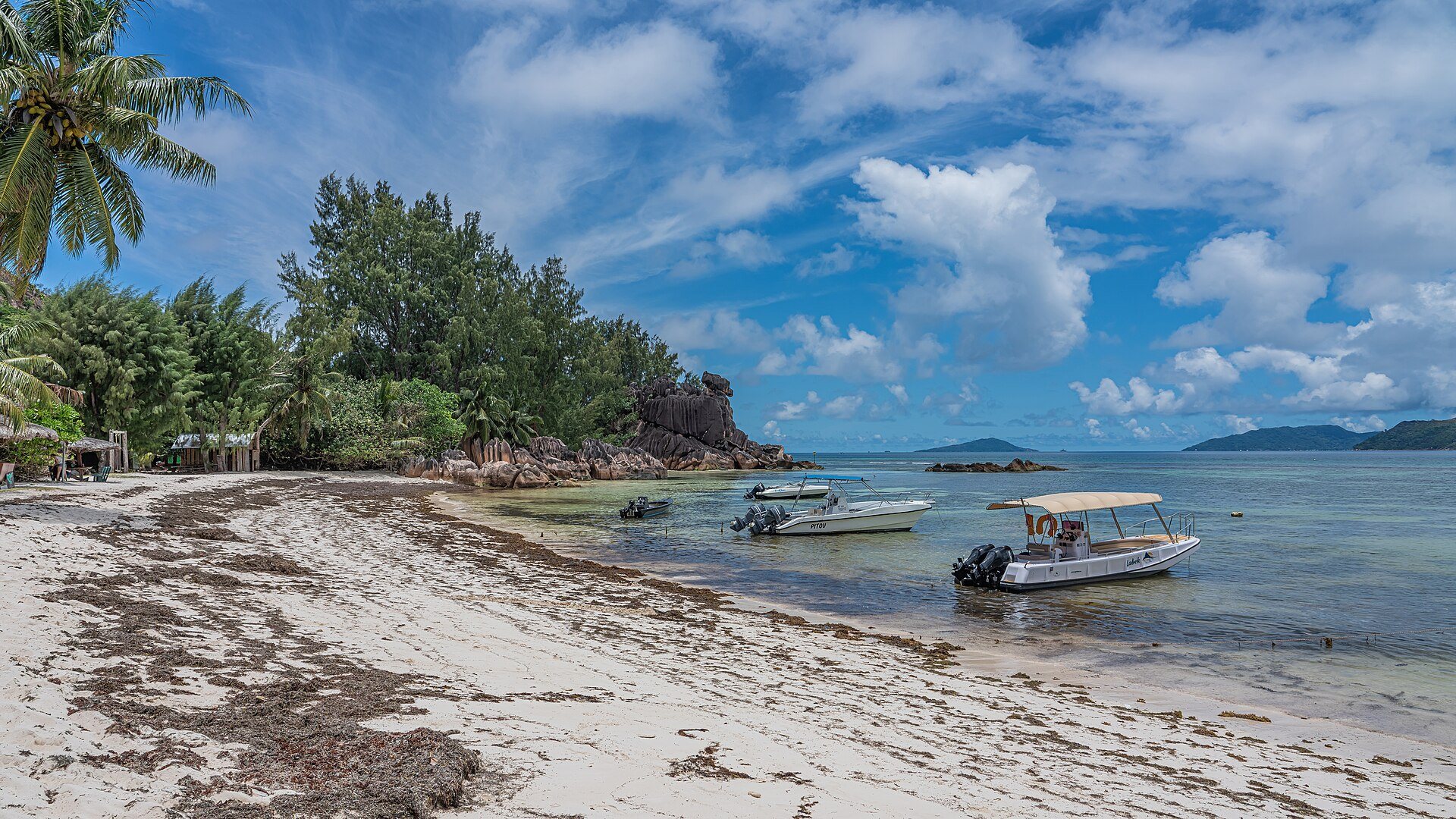 Gite in barca alle Seychelles: piccole imbarcazioni ormeggiate davanti alla spiaggia dell’isola di Curieuse